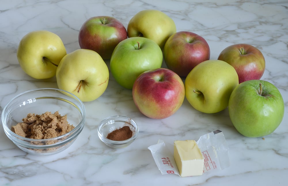 Various colored apples on a marbled countertop with butter and seasonings.
