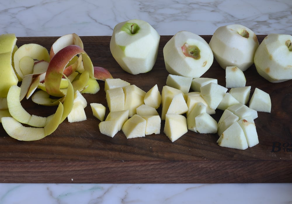 Peeled and chopped apples on a wooden cutting board.
