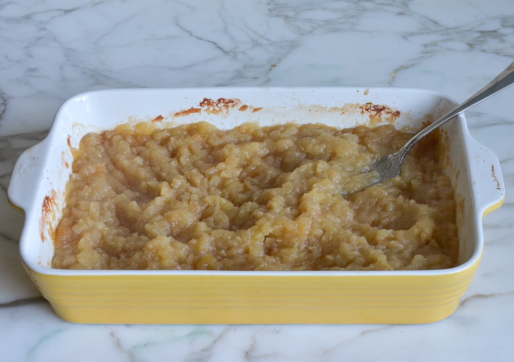 Smashed apples in a yellow baking dish.