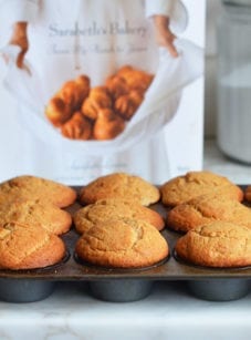 Muffin tin of maple muffins in front of a cookbook.