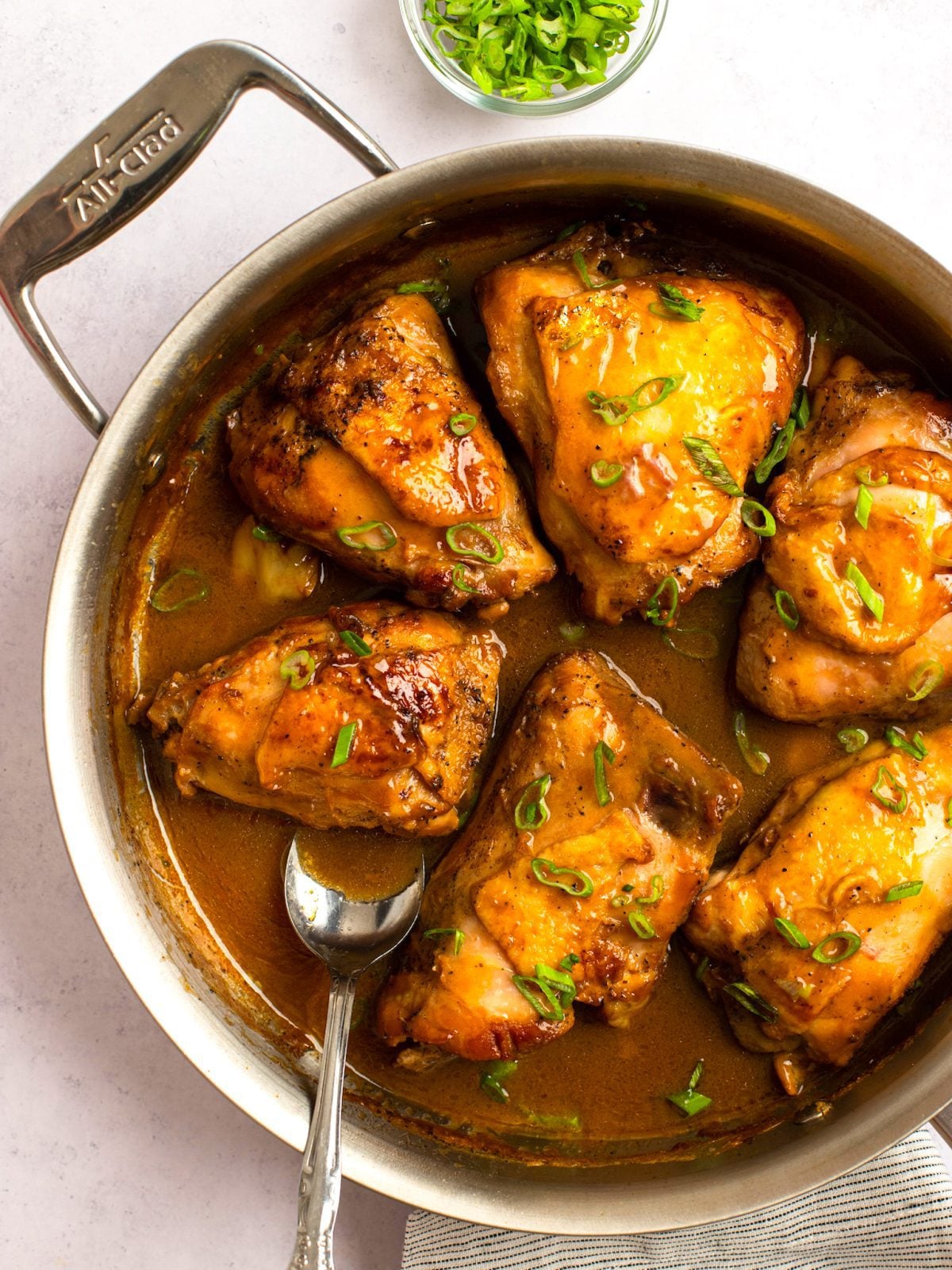 Spoon in a skillet of Filipino chicken adobo.