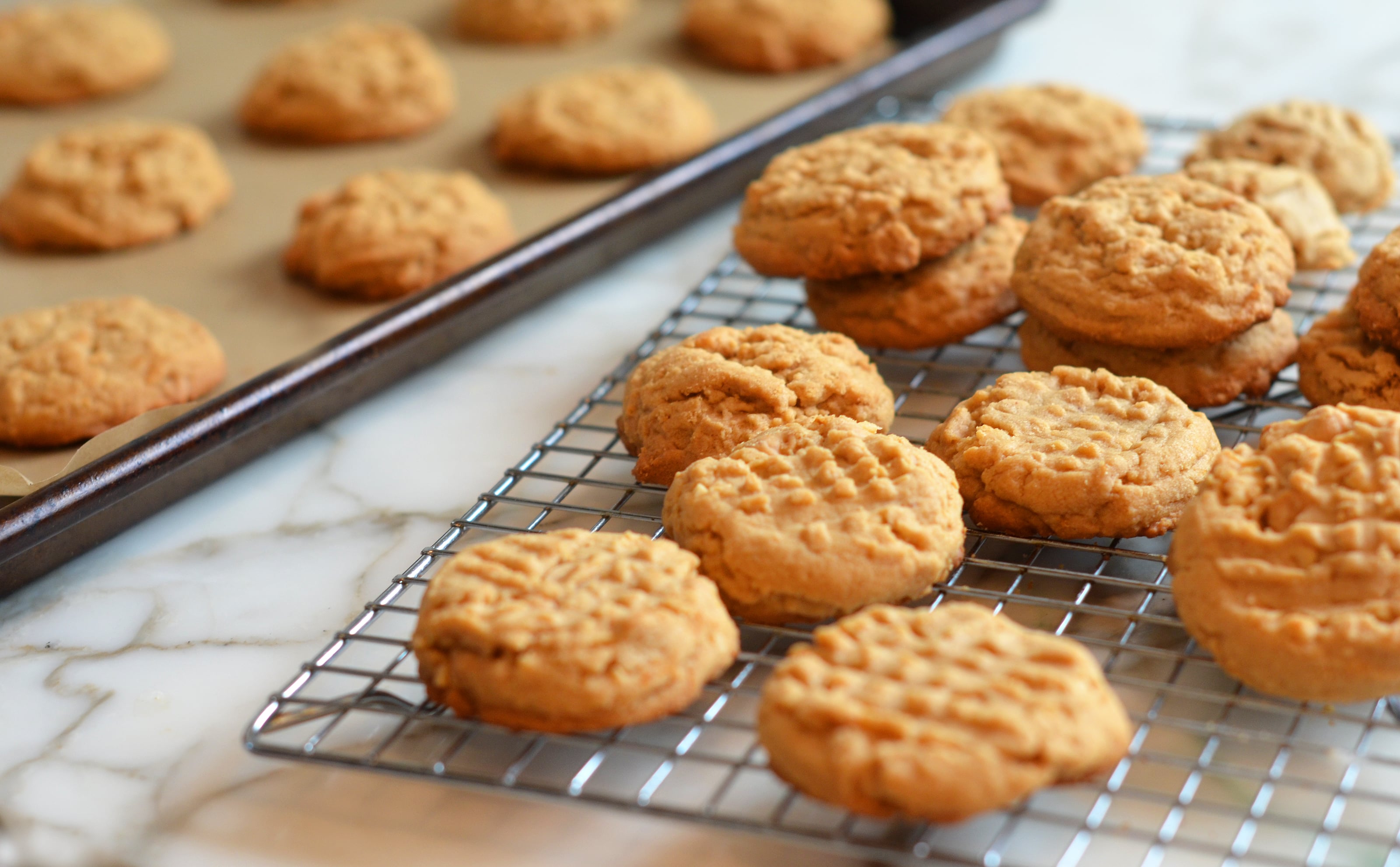 Peanut Butter Cookies cooling on a wire rack and some on a baking tray.