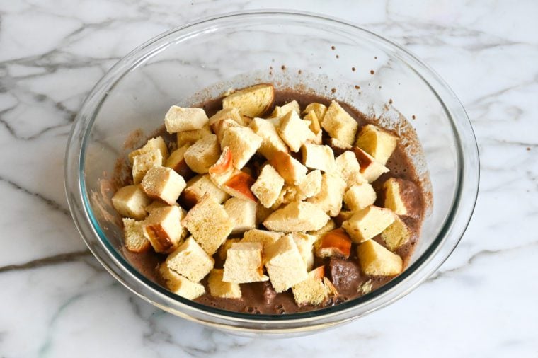 adding challah cubes to custard mixture