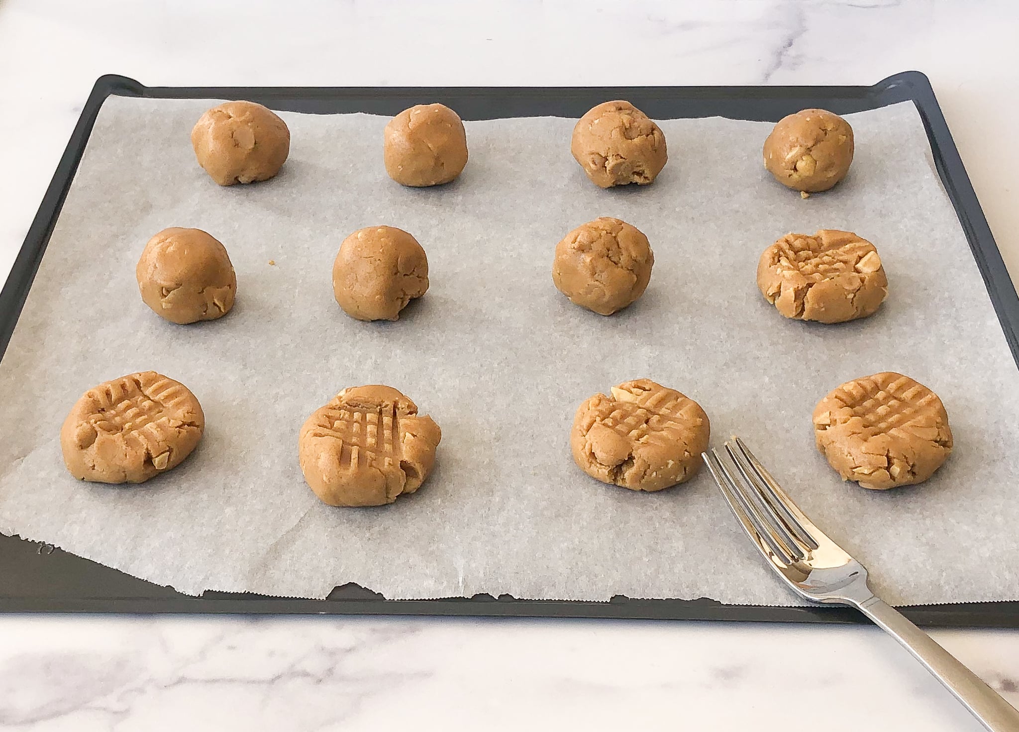 Peanut butter cookie dough balls on baking sheet.