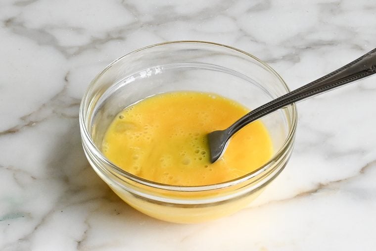 Fork in a bowl with beaten eggs.