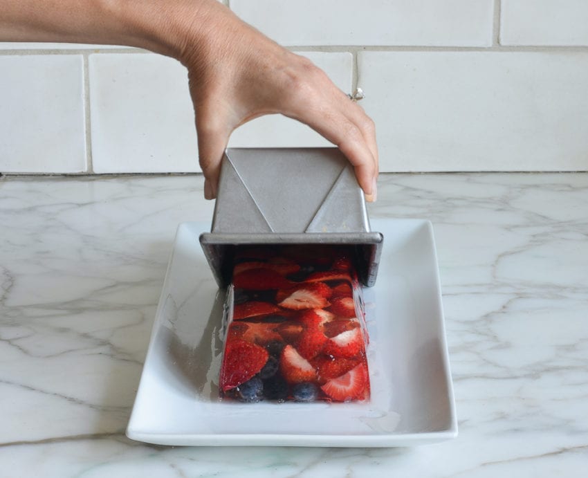 Person removing a pan from fresh berry terrine.