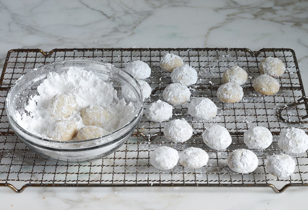 rolling Mexican wedding cookies again in confectioners sugar