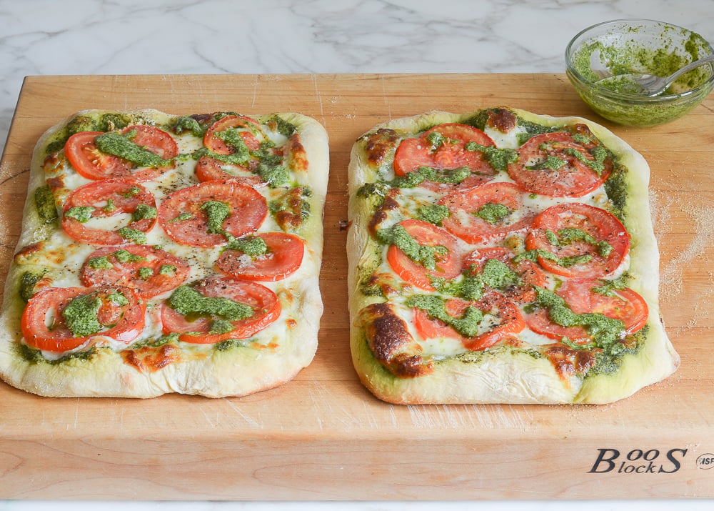 drizzling the pizzas with pesto
