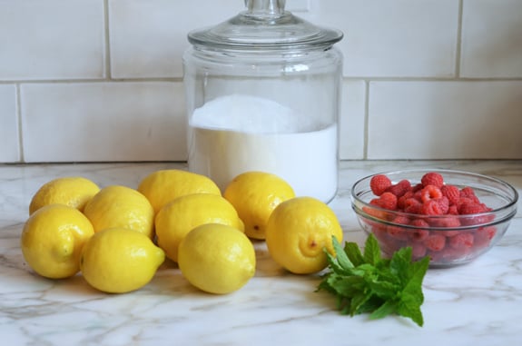 Lemonade ingredients including lemons, raspberries, and sugar.