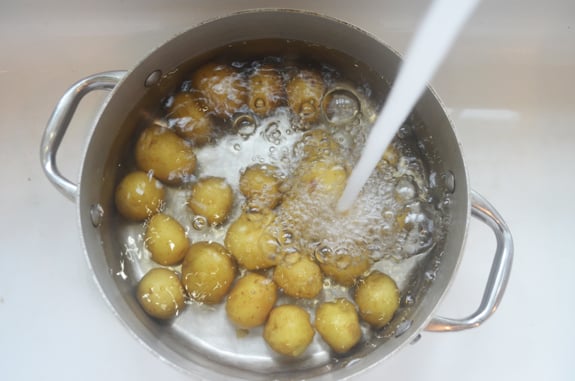 Water pouring into a pot of potatoes.