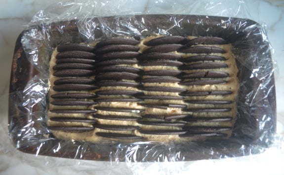 Rows of chocolate wafers in a pan of peanut butter cream.