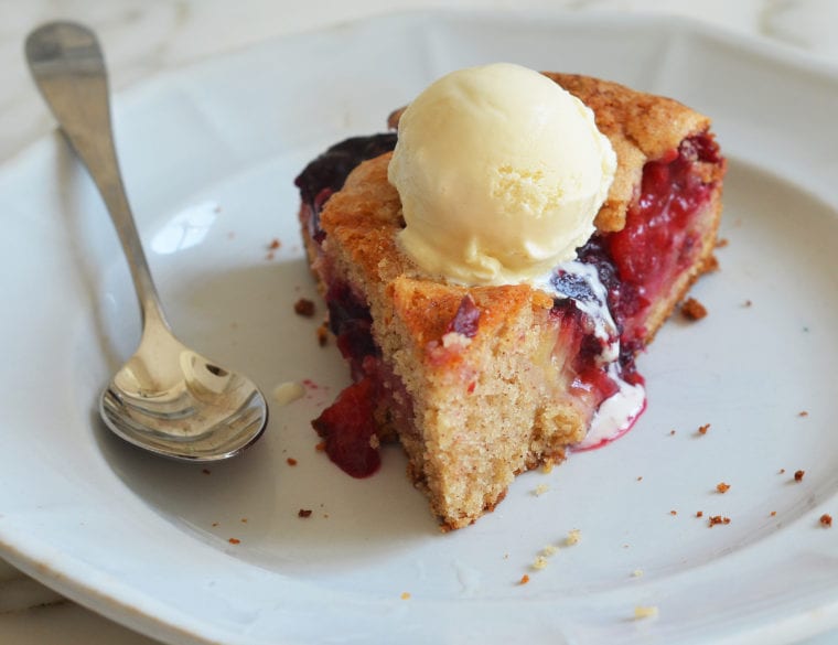 Piece of plum cake on a plate with a spoon.