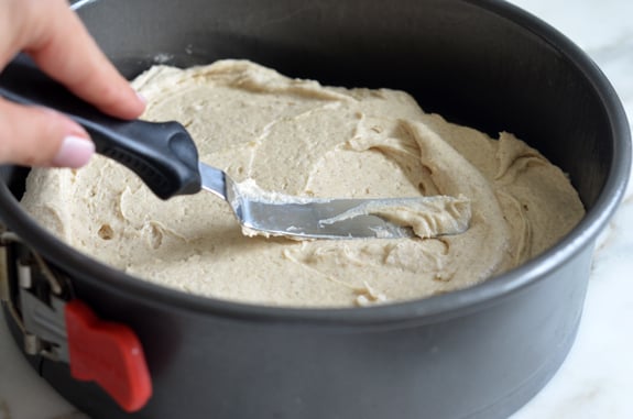 Person spreading batter into a cake pan.