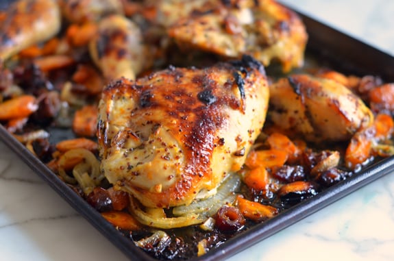 Baking sheet of sweet and spicy roast chicken with carrots, dates, and pistachios.