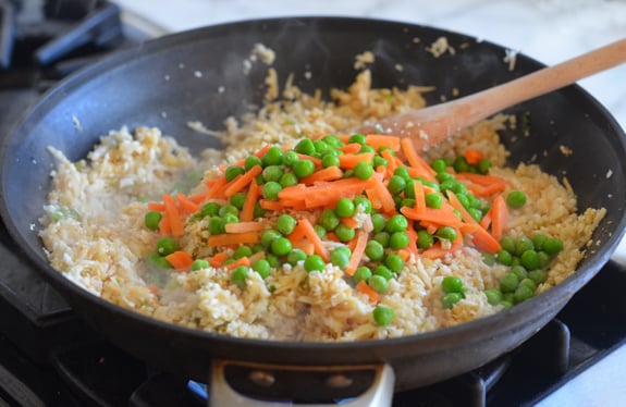 Peas and carrots in a skillet with riced cauliflower.
