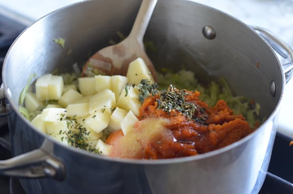 Apples, herbs, and pumpkin added to a pan with leeks.