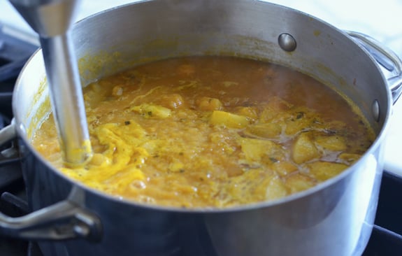 Immersion blender in a pot of soup.