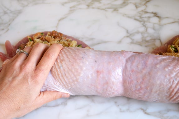 Person rolling a turkey breast around sausage and herb stuffing.