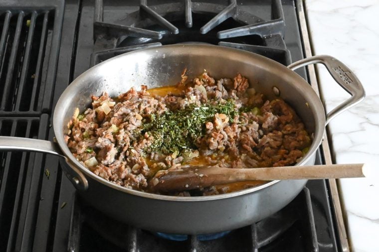 adding the wine, rosemary and thyme to the sausage mixture