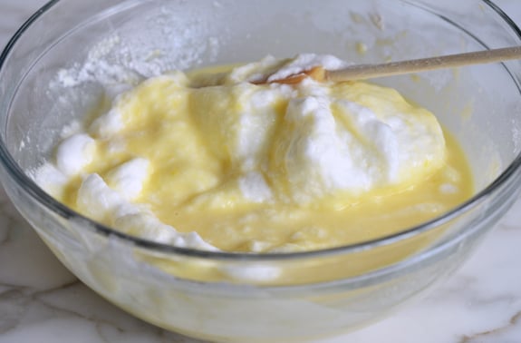 Spatula folding egg whites into a lemon mixture.