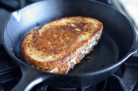 Grilled cheese and sun-dried tomato pesto sandwich in a skillet.