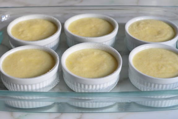 Ramekins of batter in a baking dish with water.