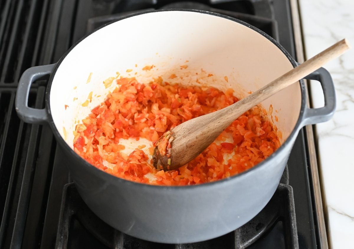 Wooden spoon in a pot of softened vegetables.