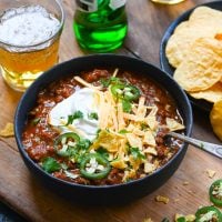 Chili in bowl with beer and tortilla chips.