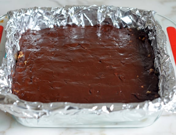 Chocolate walnut fudge in a lined baking dish.