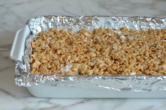 Uncut Golden Rice Krispie treats in a lined baking dish.