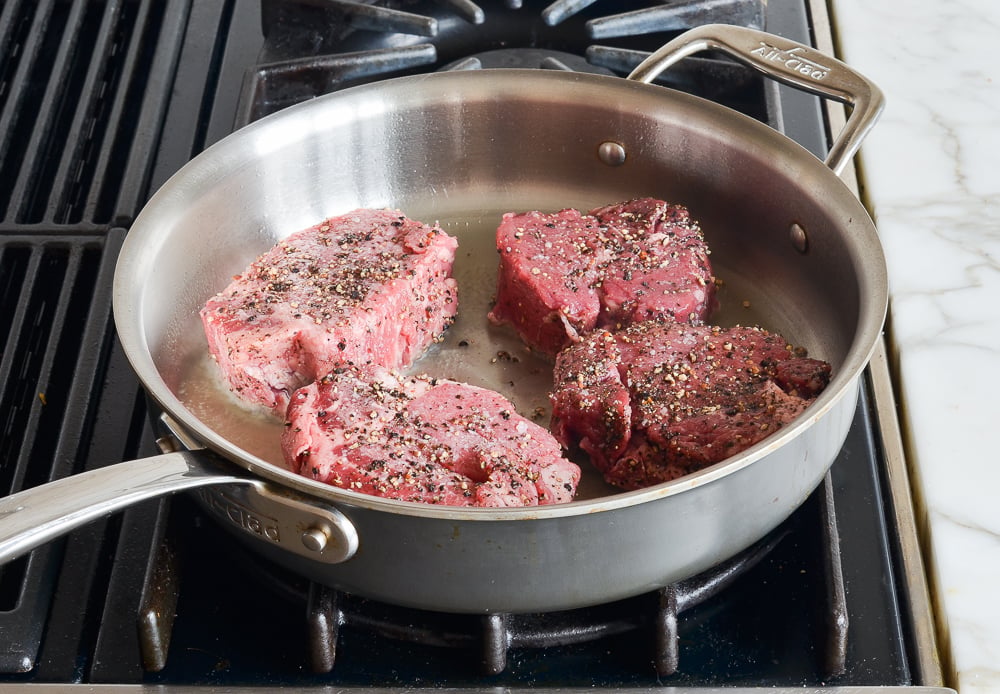 Steaks searing on the first side.
