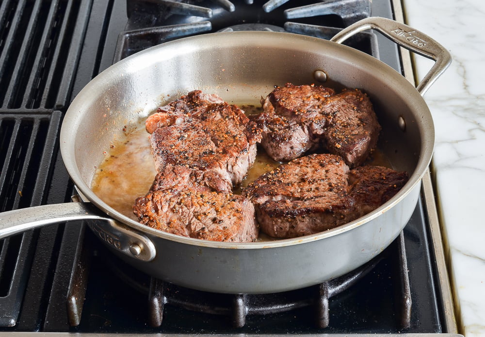 The steaks searing on second side in. askillet.