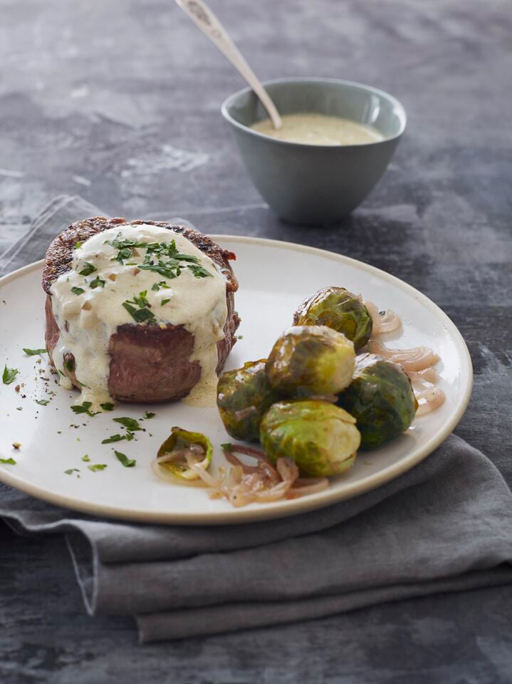 Plate of steak au poivre with brussels sprouts.