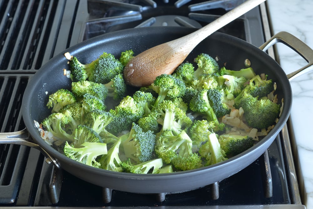 Broccoli in a skillet with shallots.