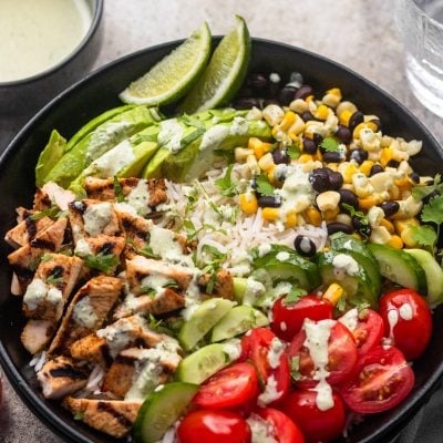 burrito bowl with green sauce and glass of water on side