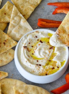 Person dipping bread into feta dip.
