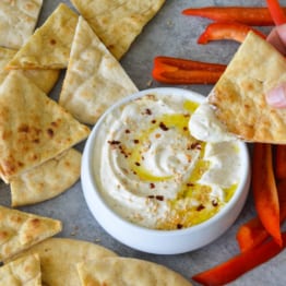 Person dipping bread into feta dip.