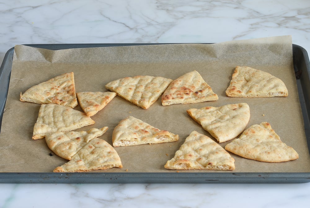 Toasted pita wedges on a lined baking sheet.