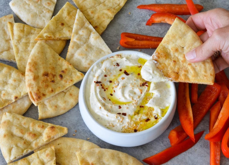 Person dipping bread into feta dip.
