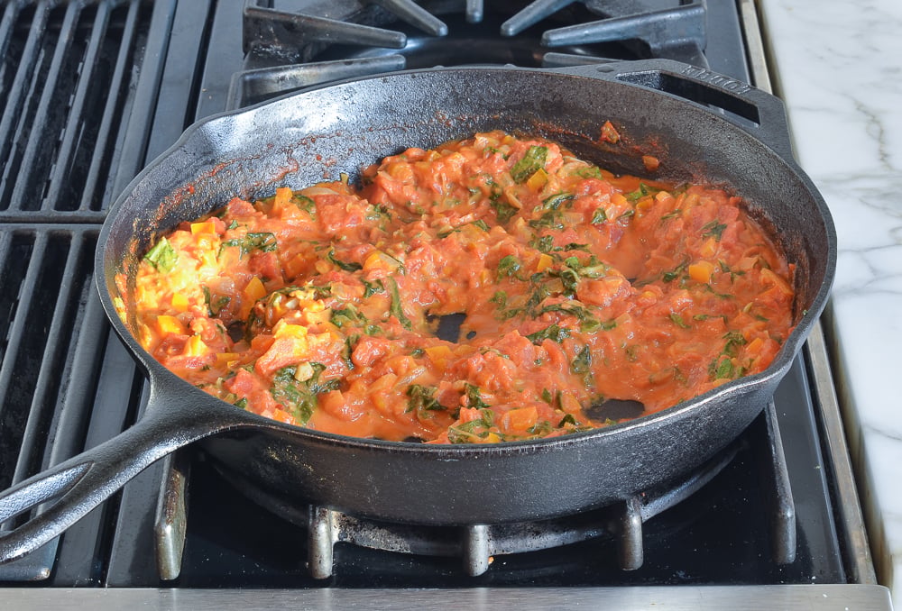 making wells in the sauce for the eggs