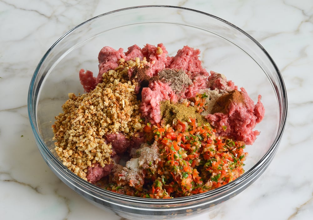 Vegetables, nuts, meat, and seasonings in a bowl.