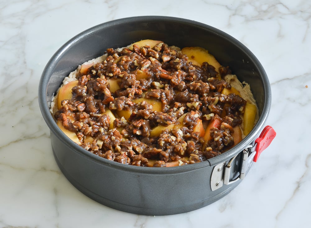 Streusel topping over peaches in a springform pan.