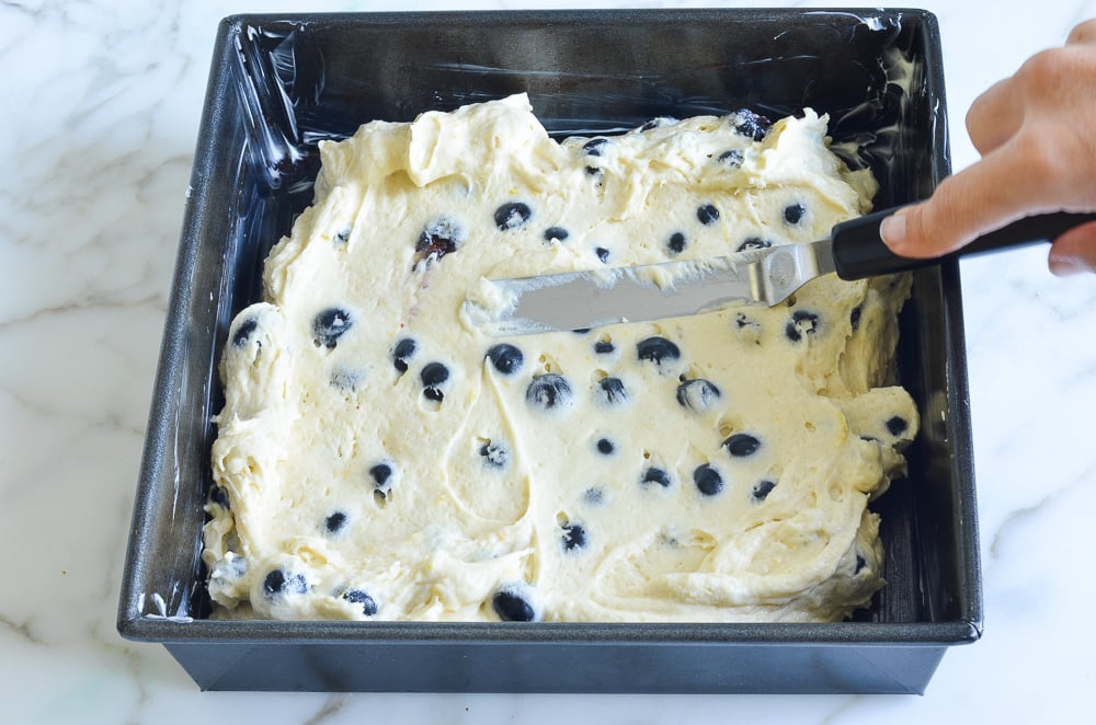 Knife spreading coffee cake batter into a baking pan.