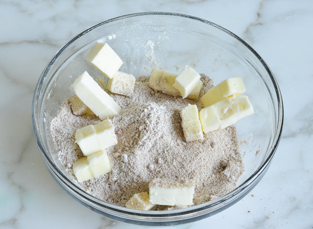 Pieces of butter in a bowl of dry ingredients.