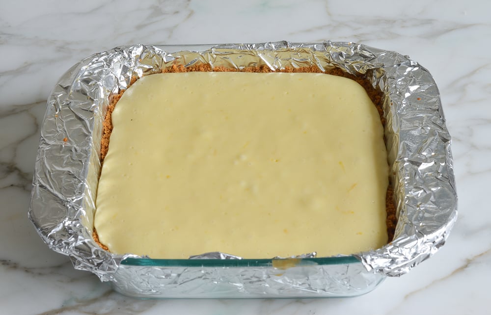 Baked cheesecake in a lined baking dish.