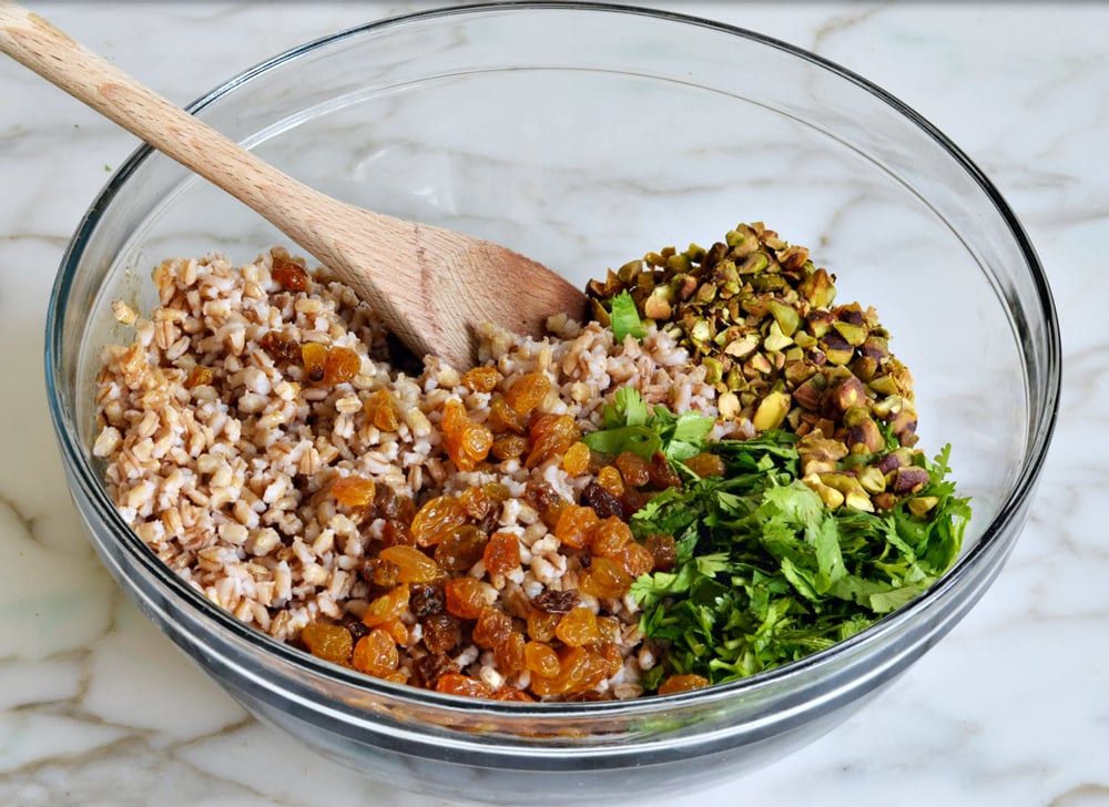 Barley in a bowl with cilantro, raisins, and pistachios.