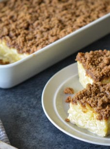 Slices of noodle kugel on a small plate next to a baking dish.