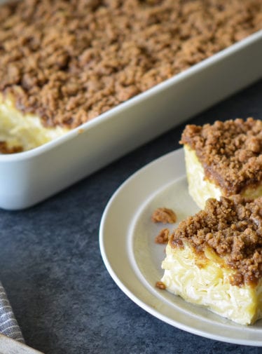 Slices of noodle kugel on a small plate next to a baking dish.