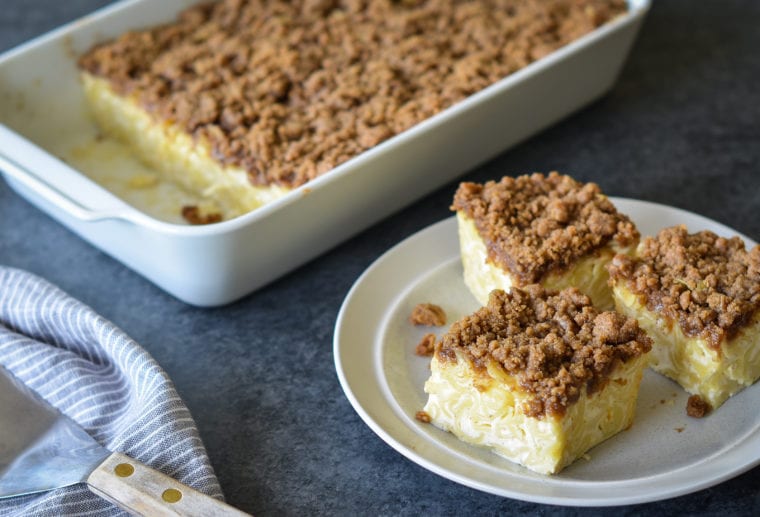 Slices of noodle kugel on a small plate next to a baking dish.