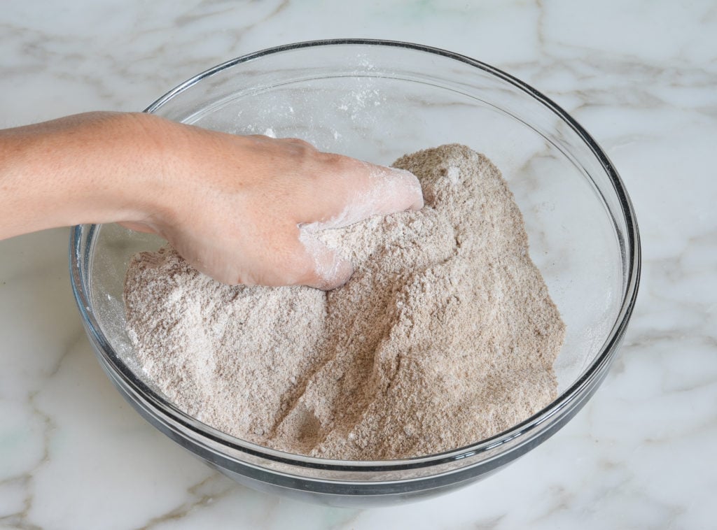 Person mixing dry ingredients by hand.
